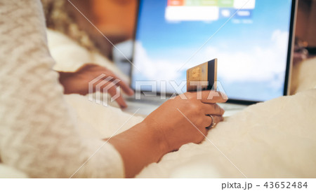 Toned closeup photo of woman making orders in online shops and stores while lying on bed with laptop Toned closeup photo of woman making orders in online shops and stores while lying on bed with laptop 43652484