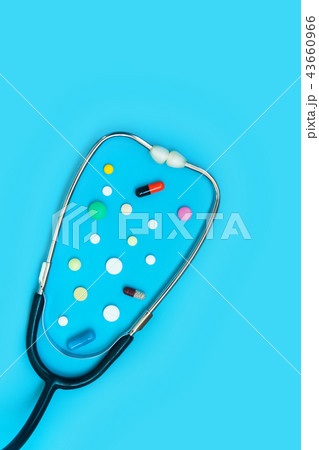 Stethoscope and different pills on blue background 43660966