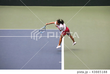 サーブを打つジュニアテニスプレイヤーの写真素材