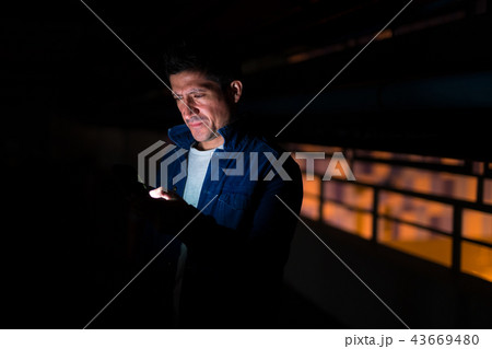 Suspicious-looking Hispanic man using phone in dark parking lot Suspicious-looking Hispanic man using phone in dark parking lot 43669480
