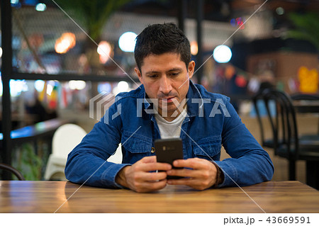 Hispanic man relaxing using phone at the restaurant Hispanic man relaxing using phone at the restaurant 43669591