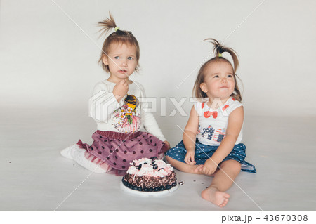 Two little baby girl eating cake white background 43670308