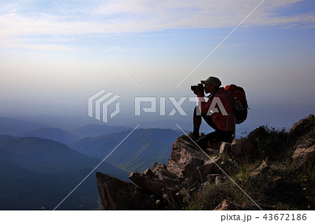 Female tourist taking photo on mountain peak Female tourist taking photo on mountain peak 43672186