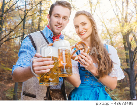 Woman and man in Bavarian Tracht drinking beer 43673499