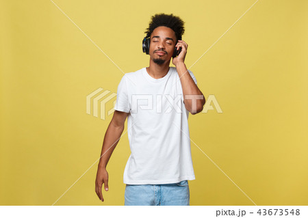 Close up portrait of dark skinned man with closed eyes, has headphones, listens to favourite music 43673548