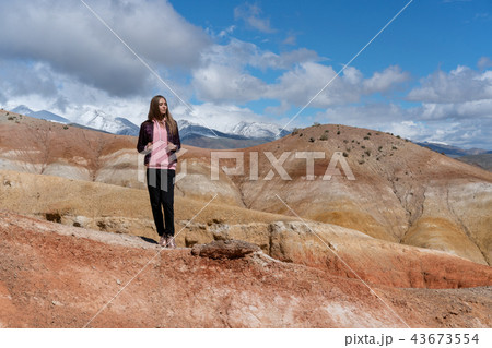 The girl stands on a hill, mountains on background The girl stands on a hill, mountains on background 43673554