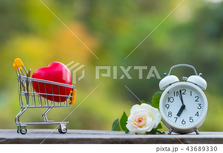 Red heart shape in shopping cart and white clock Red heart shape in shopping cart and white clock 43689330