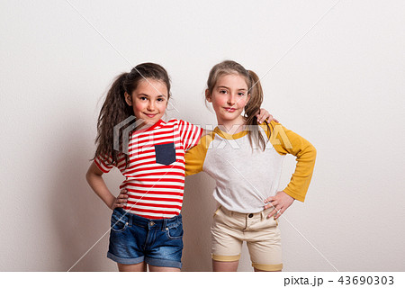 Small girls standing in a studio, arms aroud each other. 43690303