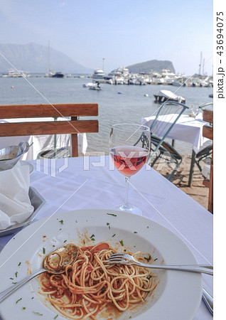 spaghetti and wine glass on table by sea spaghetti and wine glass on table by sea 43694075