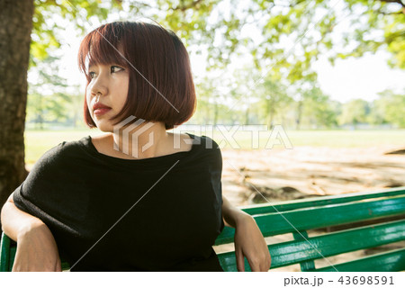 woman sit alone on the public bench in the park. woman sit alone on the public bench in the park. 43698591