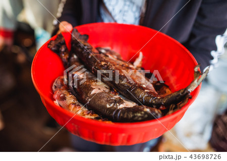 man holding Grilled fish in red Bowl 43698726