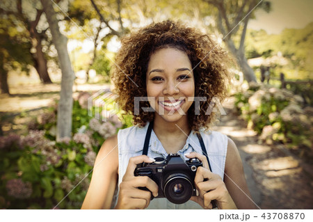 Portrait of smiling woman standing with digital camera 43708870