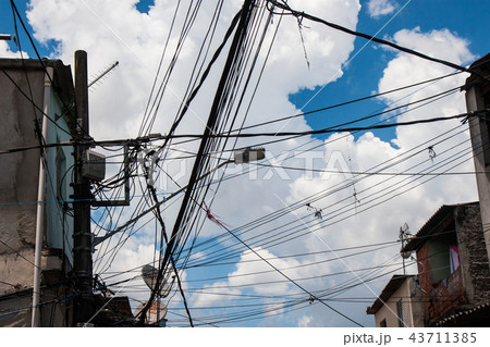 Electric wires in a slum with cloudy sky. 43711385