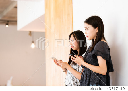 スマホを操作する女性二人 43717110