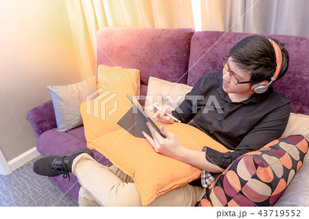 Asian man using tablet on sofa in living room Asian man using tablet on sofa in living room 43719552