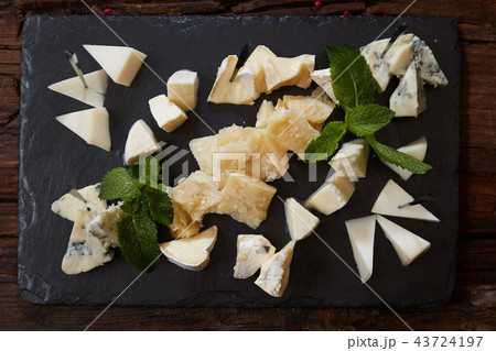 Cheeseboard Top View on Black Stone Plate Background Cheeseboard Top View on Black Stone Plate Background 43724197