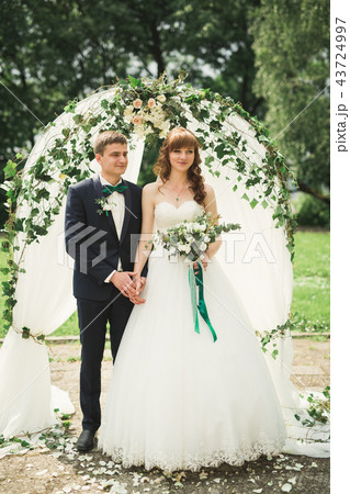 Romantic, fairytale, happy newlywed couple hugging and kissing in a park, trees in background 43724997