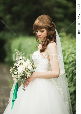 Portrait of stunning bride with long hair posing with great bouquet 43724998