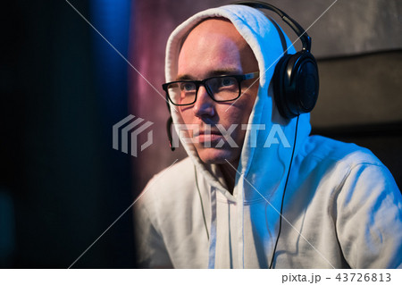 Portrait of concentrated young man in glasses and headset in dark room playing online computer game 43726813