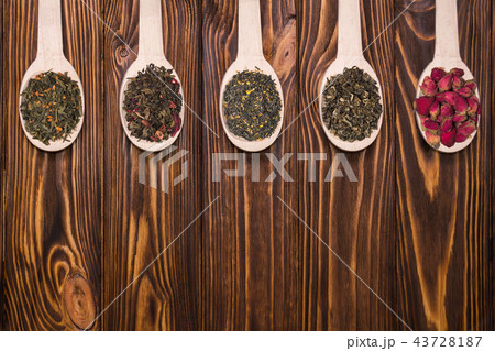 Set of different dry herbal teas in wooden spoons on a white background 43728187