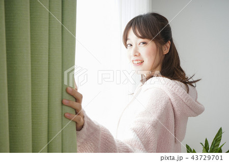 起きて部屋のカーテンを開ける若い女性 43729701