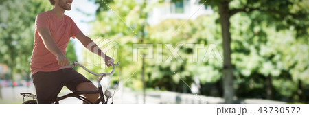 Composite image of handsome man on a bike ride on a sunny day 43730572