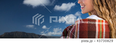 Composite image of smiling beautiful woman wrapped in blanket 43730829