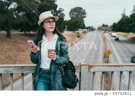 woman holding coffee and phone on bridge woman holding coffee and phone on bridge 43732611
