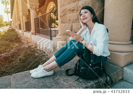 female sitting on stone and listen to music 43732633