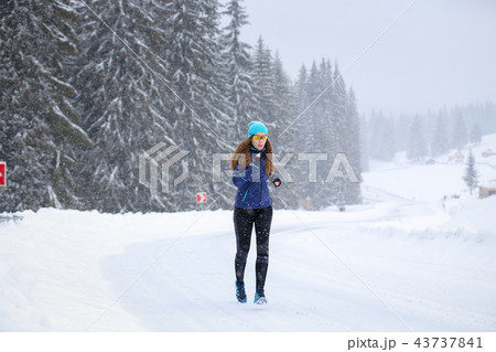 Young woman running on the mountain road in winter 43737841
