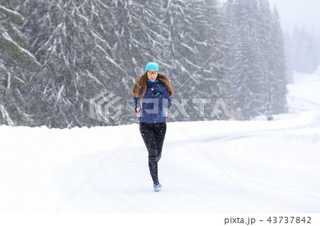 Young woman running on the mountain road in winter 43737842
