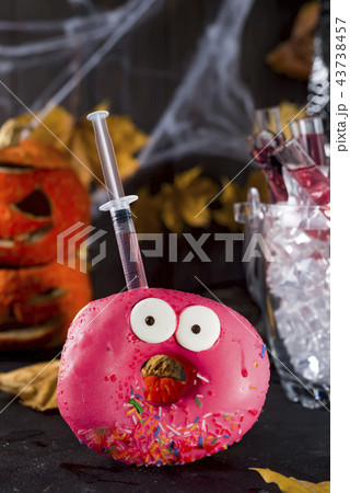 Dishes with glazed donuts, with a red cocktail in a glass tube in a bucket of ice, in the background 43738457