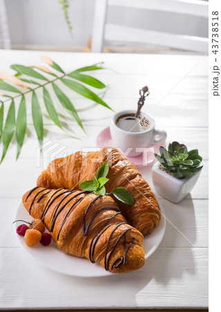 Continental breakfast freshly baked croissant decorated with jam and chocolate on wooden table in a 43738518