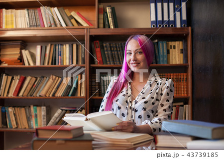 woman with pink hair reads books in the library 43739185