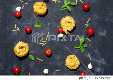 Pasta pattern. Several types of dry pasta with vegetables and herbs on a dark stone table. Free Pasta pattern. Several types of dry pasta with vegetables and herbs on a dark stone table. Free 43739299