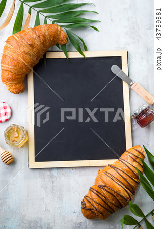 Traveled breakfast with croissants, honey, jam and berries on the trip. Background of a chalkboard Traveled breakfast with croissants, honey, jam and berries on the trip. Background of a chalkboard 43739381