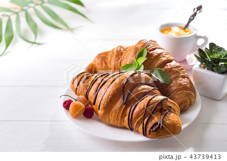 Continental breakfast freshly baked croissant decorated with jam and chocolate on wooden table in a 43739413