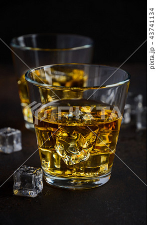 Glass of whiskey with ice on dark background Glass of whiskey with ice on dark background 43741134
