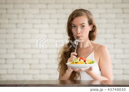 Young woman with salad on folk and salad bowl 43749030