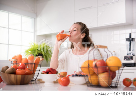 Woman in a kitchen with fruits and juice Woman in a kitchen with fruits and juice 43749148