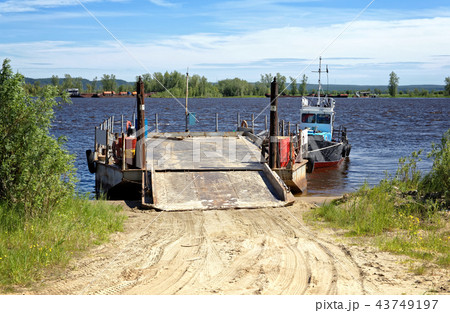River barge with ramp and boat on the pier near the shore waiting for loading River barge with ramp and boat on the pier near the shore waiting for loading 43749197