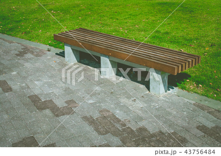 Wooden long bench setting on concrete walkway. 43756484