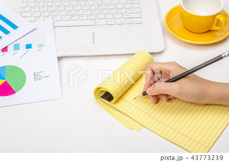A note taking notes on a notepad in an office A note taking notes on a notepad in an office 43773239