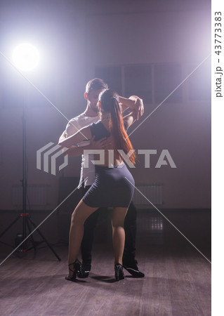 Skillful dancers performing in the dark room under the concert light and smoke. Sensual couple 43773383