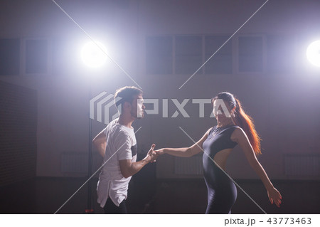 Skillful dancers performing in the dark room under the concert light and smoke. Sensual couple Skillful dancers performing in the dark room under the concert light and smoke. Sensual couple 43773463