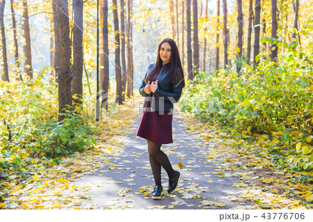 Autumn, nature, people concept - young beautiful woman walking in autumn park in red dress and black 43776706