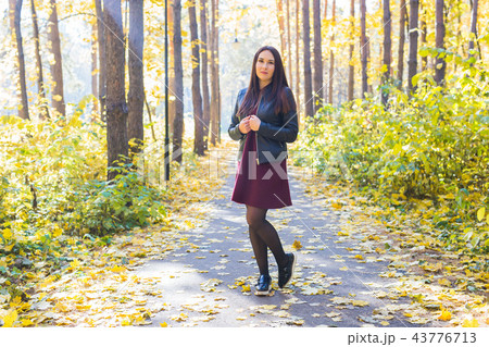 Nature, season and people concept - Fashion woman walking in autumn park 43776713