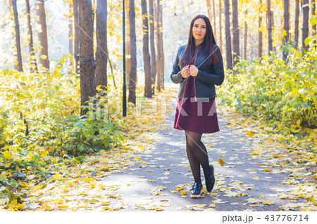 People, season and nature concept - Young woman walking in autumn park 43776714