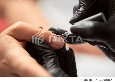 Close-up of beautician hands applying transparent gel polish on woman fingernails in beauty salon. Close-up of beautician hands applying transparent gel polish on woman fingernails in beauty salon. 43778002