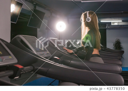 Fitness woman running on treadmill. Girl with muscular legs in gym 43778350